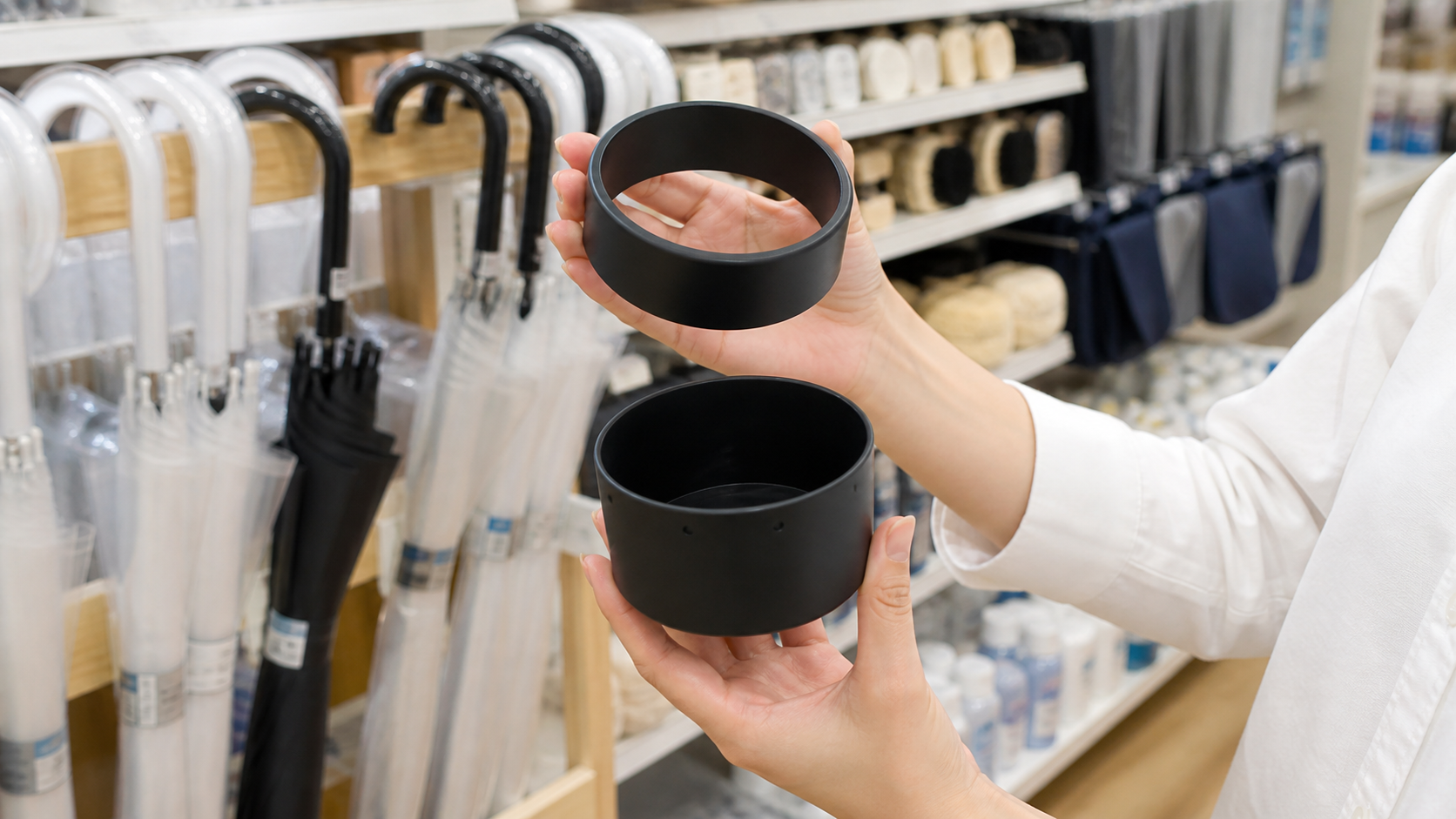 100円ショップの傘・レイングッズ売り場で黒いマグネット式傘ホルダーを探すイメージ