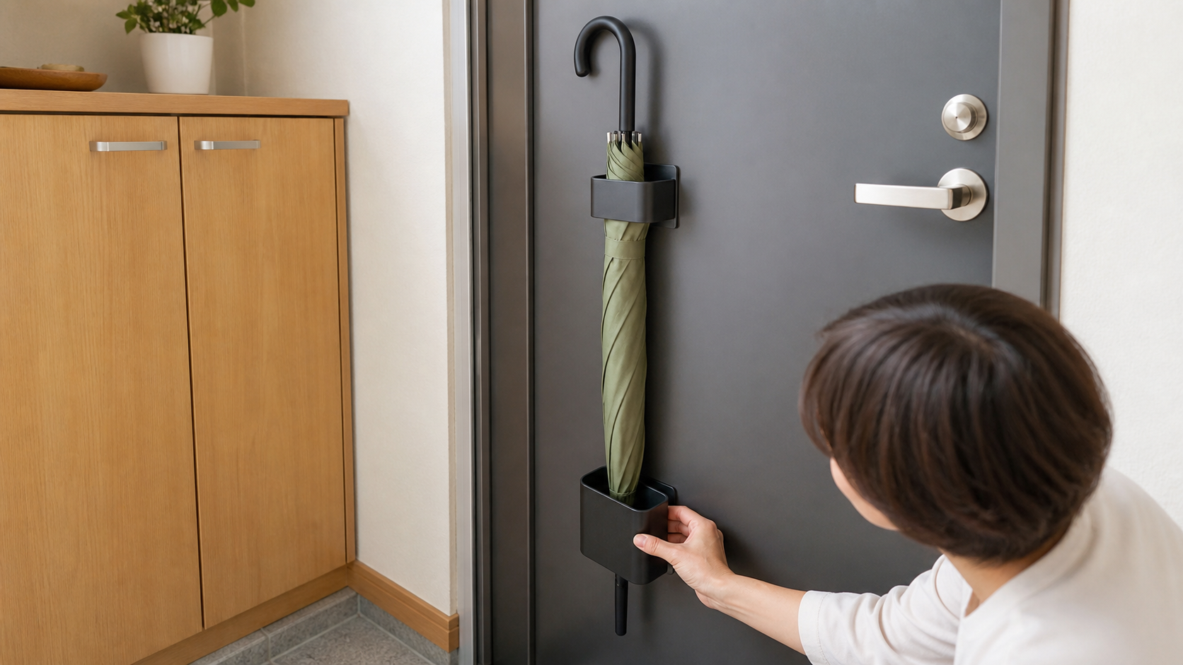 鉄製の玄関ドアに黒い上下分離型マグネット傘ホルダーを垂直に取り付けるイメージ